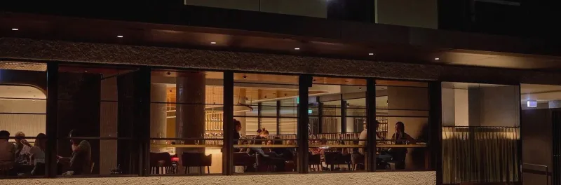 The lit glass frontage of 81 Bay and Baix on Bay Street at night