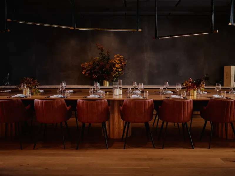 The Vasari Room communal table lined with tan leather chairs under low lighting
