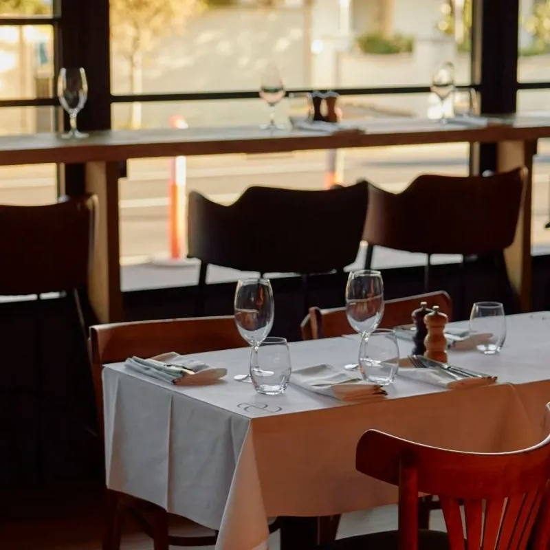 Table for two set with wine glasses in the window looking out to Bay Street, Brighton