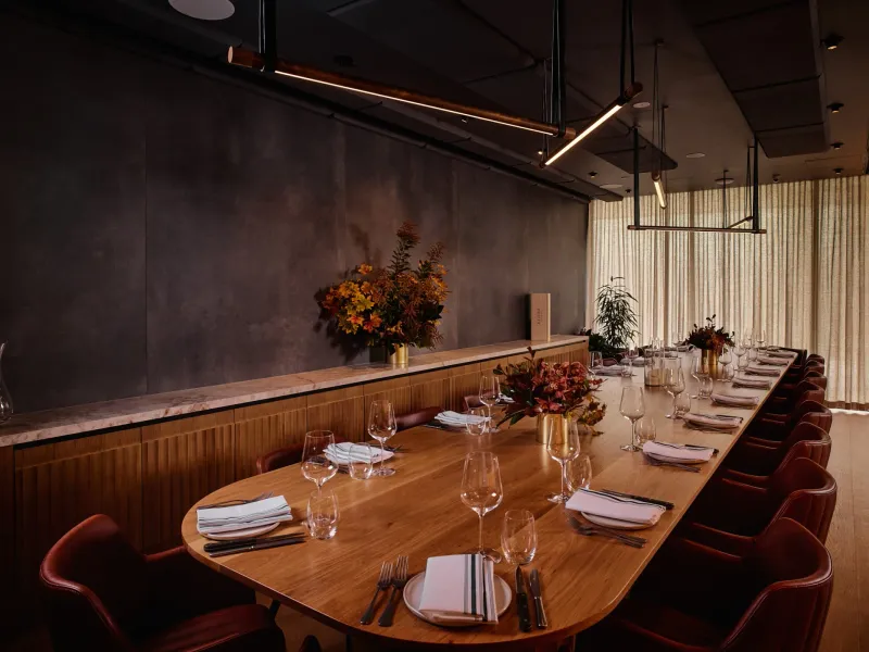 Long oval timber table in the Vasari Room set with glassware and autumn flowers