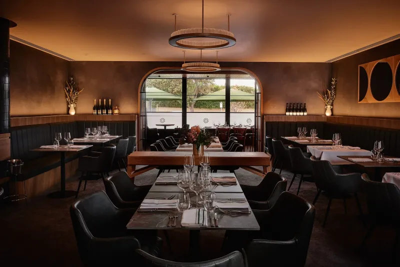 Baix restaurant dining room in Brighton with green leather booths, marble tables and an arched window