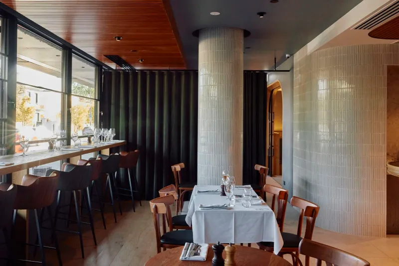 Daylight through the front windows at 81 Bay, bar stools along the counter and a fluted column